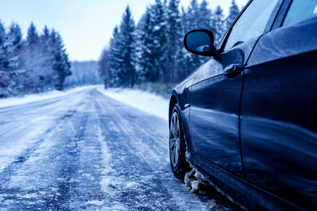 black car iced road surrounded by trees covered with snow 1